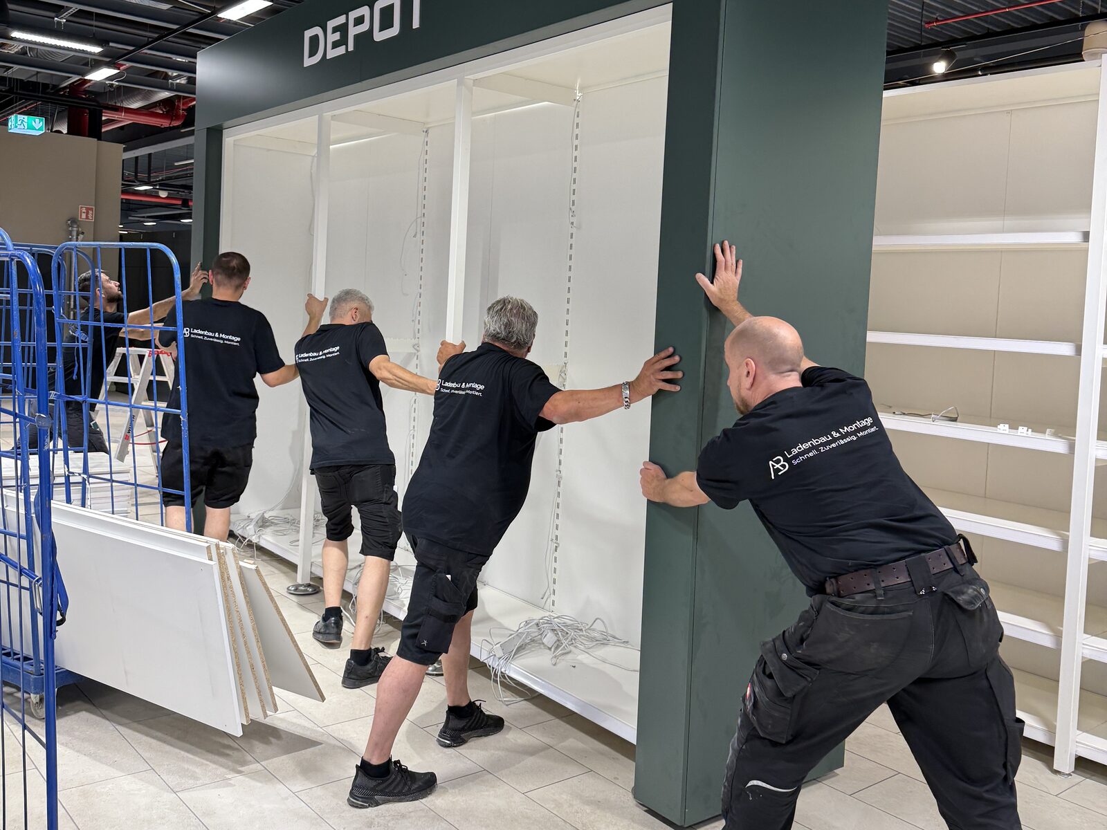 Montageteam von A.B. Ladenbau und Montage richtet einen Warenträger in einer Verkaufsfläche aus